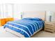 Bright bedroom featuring a bed with blue striped bedding and a wooden dresser at 8979 Grey Oaks Ave, Sarasota, FL 34238