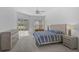 Well-lit main bedroom featuring a large bed, dresser, end tables, and sliding glass doors to the lanai at 8979 Grey Oaks Ave, Sarasota, FL 34238