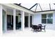 Relaxing outdoor patio featuring white brick pavers and a set of dark wicker furniture at 8979 Grey Oaks Ave, Sarasota, FL 34238