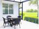 Outdoor patio with wicker furniture and a beautiful green view of the adjacent golf course at 8979 Grey Oaks Ave, Sarasota, FL 34238