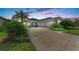 Beautiful home exterior with well-manicured landscaping, long driveway, and attached two-car garage at dusk at 1219 Thornbury Dr, Parrish, FL 34219