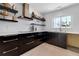 Contemporary kitchen featuring stylish dark cabinets, floating shelves, and modern appliances at 130 N Adams Dr, Sarasota, FL 34236