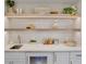 Bright bar area featuring floating wood shelves, a beverage fridge, and ample counter space at 135 Avenida Veneccia, Sarasota, FL 34242