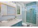 Bright bathroom features a blue vanity, large mirror, and glass-enclosed shower with decorative tile at 135 Avenida Veneccia, Sarasota, FL 34242
