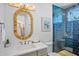Charming bathroom with blue-tiled shower, a stylish oval mirror, and modern vanity at 135 Avenida Veneccia, Sarasota, FL 34242