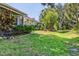 A green backyard and the house's exterior are enhanced by well-maintained landscaping at 1516 Red Oak Ln, Port Charlotte, FL 33948
