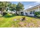 Lush green lawn, trees and colorful flowers adorn the home's backyard at 1516 Red Oak Ln, Port Charlotte, FL 33948