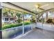 Enclosed lanai area featuring a ceiling fan and view of the landscaped backyard at 1516 Red Oak Ln, Port Charlotte, FL 33948