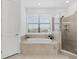 Bright bathroom features a soaking tub, a tiled shower, and a large window at 15315 Golden Beam Pl, Bradenton, FL 34211