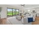 Bright living room with plush seating, ceiling fan, wood floors, and views to the landscaped backyard through sliding glass doors at 15315 Golden Beam Pl, Bradenton, FL 34211