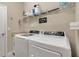 Well-lit laundry room featuring a washer, dryer, storage shelf with supplies and a convenient utility sink at 15607 White Linen Dr, Bradenton, FL 34211