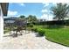 Landscaped backyard with screened lanai featuring stone pavers and dining table at 1919 Woodleaf Hammock Ct, Bradenton, FL 34211