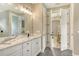Bright bathroom with double doors, an elegant vanity with white cabinets, and a view of a bedroom at 1919 Woodleaf Hammock Ct, Bradenton, FL 34211