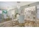 A modern dining room with a glass-top table, white chairs, and a view into the updated kitchen at 2055 Gulf Of Mexico Dr # G2-108, Longboat Key, FL 34228
