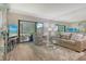 A bright living room with a large sliding door, comfortable seating, and a decorative glass shelving unit at 2055 Gulf Of Mexico Dr # G2-108, Longboat Key, FL 34228