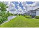 View of the lush green backyard and pond behind the home with screened-in patios at 2631 Sapphire Blue Ln, Bradenton, FL 34211