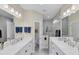 Bathroom featuring dual sinks, white cabinets, decorative mirrors, and a glass-enclosed shower at 2631 Sapphire Blue Ln, Bradenton, FL 34211