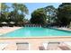 Large swimming pool with lounge chairs and umbrellas surrounded by shade trees at 2650 Coconut Bay Ln # 521, Sarasota, FL 34237