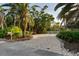 Paver driveway leading to the house surrounded by tropical landscaping and a white fence at 3446 Anglin Dr, Sarasota, FL 34242