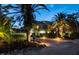 Inviting home exterior with lush landscaping, palm trees, and a charming brick driveway at twilight at 3446 Anglin Dr, Sarasota, FL 34242
