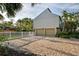 Spacious garage with a wide paver driveway, complimented by tropical trees and a white fence at 3446 Anglin Dr, Sarasota, FL 34242