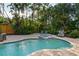 Sun-drenched backyard pool and spa with grill, lounge chairs, and patio seating amidst tropical landscaping at 3446 Anglin Dr, Sarasota, FL 34242