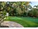 Landscaped backyard putting green with lush foliage, stone pathway and white fence at 3446 Anglin Dr, Sarasota, FL 34242