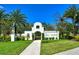 Community entrance with white walls, lush landscaping and sidewalk leading to the DEL TIERRA gate at 364 Grande Vista Blvd, Bradenton, FL 34212