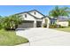 Charming home with a well-kept lawn, three-car garage, and lush landscaping, all under a bright blue sky at 364 Grande Vista Blvd, Bradenton, FL 34212