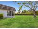 Well-maintained backyard with a lush lawn, mature trees, and a partial view of the home at 3816 Blue Stone Way # 97, Sarasota, FL 34232