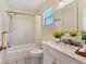 Bathroom featuring marble countertop, single sink vanity, and shower over tub with white tile surround at 3816 Blue Stone Way # 97, Sarasota, FL 34232