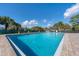 Community pool with blue water, ladder, safety ring, and brick trim under a sunny sky at 3816 Blue Stone Way # 97, Sarasota, FL 34232