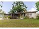 View of the front of the home featuring a screened in porch, landscaping, and lush green lawn at 4015 Asbury Pl, Sarasota, FL 34233