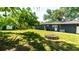 Back exterior with green lawn, mature trees, and fire pit at 4310 7Th W Ave, Bradenton, FL 34209