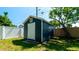 View of a navy blue shed with a white door in a fenced yard with lush green grass at 4310 7Th W Ave, Bradenton, FL 34209