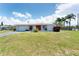 Single-story home featuring a bright red front door and well-manicured front yard with mature trees at 4535 Maceachen Blvd, Sarasota, FL 34233