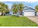 Inviting blue single-story home with well-manicured lawn, palm trees, and a two-car garage at 4844 14Th E Ave, Bradenton, FL 34208