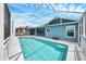 A refreshing screened pool with clear blue water, attached to a blue home with a gray roof at 4844 14Th E Ave, Bradenton, FL 34208