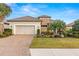 Charming single-story home featuring a tile roof, brick driveway, two-car garage, and lush landscaping at 5011 Tivoli Run, Bradenton, FL 34211