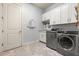 Well-lit laundry room featuring modern stainless steel appliances and ample cabinet storage at 5011 Tivoli Run, Bradenton, FL 34211