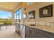 Covered outdoor kitchen with granite counters, cabinetry, and lovely view of a lake at 5011 Tivoli Run, Bradenton, FL 34211