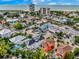 An aerial view of a coastal neighborhood with colorful buildings, lush greenery, and views of the ocean at 5219 Calle Menorca, Sarasota, FL 34242
