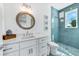 Stylish bathroom features a vanity with round mirror and a walk-in shower with blue tile at 5219 Calle Menorca, Sarasota, FL 34242
