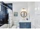 Stylish bathroom features a navy blue vanity with a marble countertop, mirror, and herringbone tile in the shower at 5219 Calle Menorca, Sarasota, FL 34242