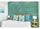 This bedroom is decorated with a green accent wall, white bedding, and blue decorative pillows at 5219 Calle Menorca, Sarasota, FL 34242