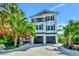 Inviting three-story beach house with a balcony and lush tropical landscaping at 5219 Calle Menorca, Sarasota, FL 34242