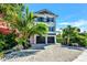 Charming three-story home with a balcony and a two-car garage nestled among palm trees at 5219 Calle Menorca, Sarasota, FL 34242