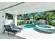 Beautiful pool and hot tub, with a rock slide and palm trees, surrounded by a white fence and patio furniture at 5219 Calle Menorca, Sarasota, FL 34242