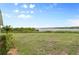 Expansive backyard featuring lush green grass and serene waterfront views under a clear, blue sky at 550 Tampico Dr, North Port, FL 34287