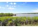 Scenic waterfront view with lush green foliage and a tranquil body of water under a bright blue sky at 550 Tampico Dr, North Port, FL 34287